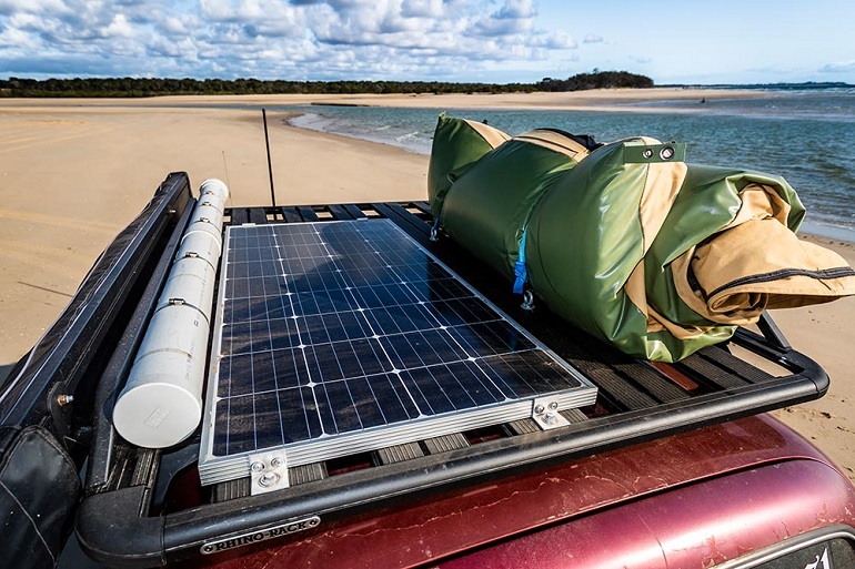 Solar panel and camping extras on SUV in beach