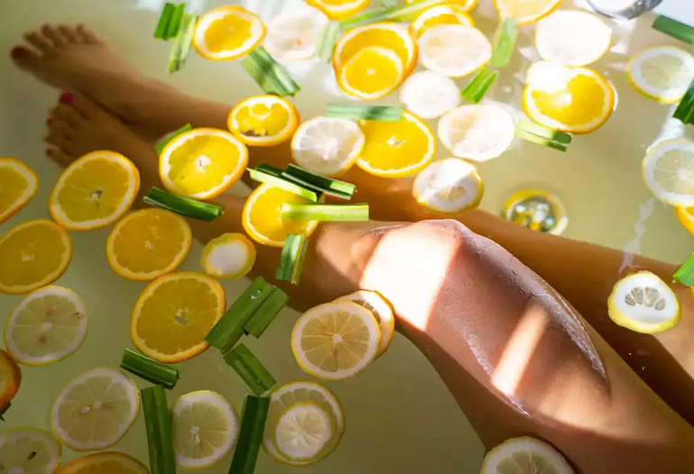 girl's legs resting in benefitial water with yuzu fruit