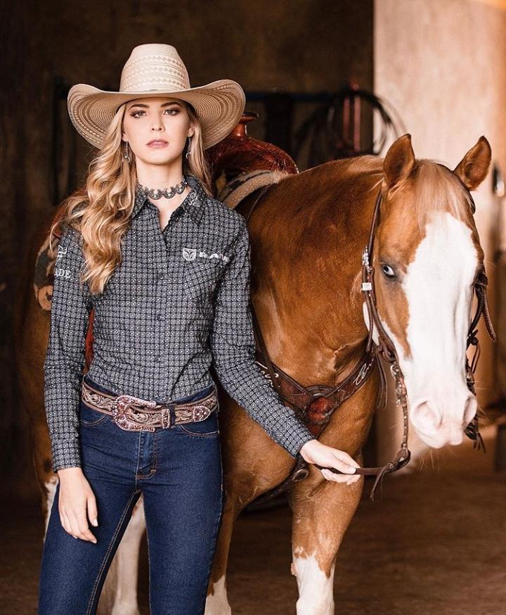 woman wearing western cowboy outfit standing next to a house