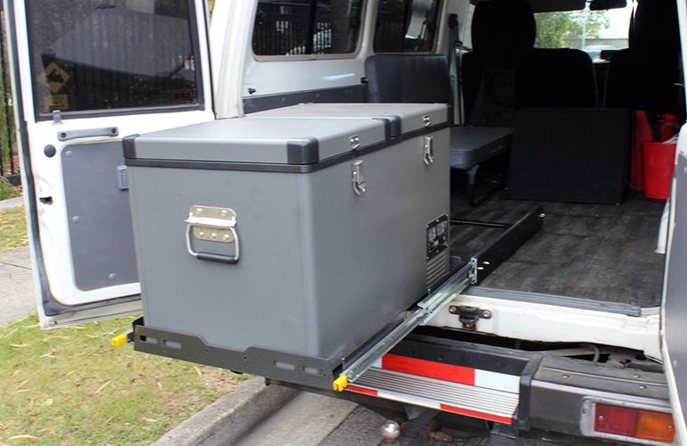 A close-up of a fridge slide installed in a vehicle, with a large storage box securely mounted on the slide, making it convenient to access items during travel.